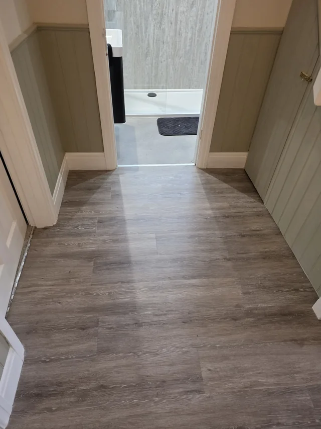 Wood-effect full-plank LVT in the hallway leading to the threshold of a shower room