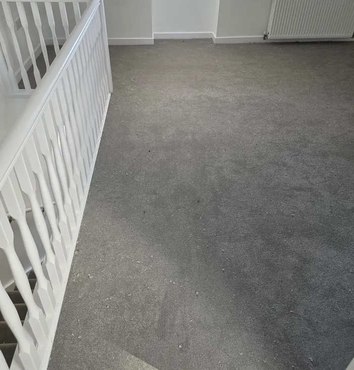 Grey carpet fitted in a loft bedroom beside white balustrades