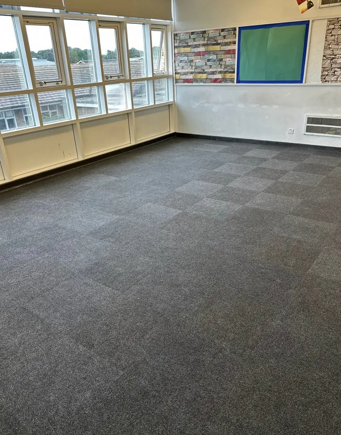 Grey carpet tiles fitted in a Bridlington school classroom with large windows and a blue display board