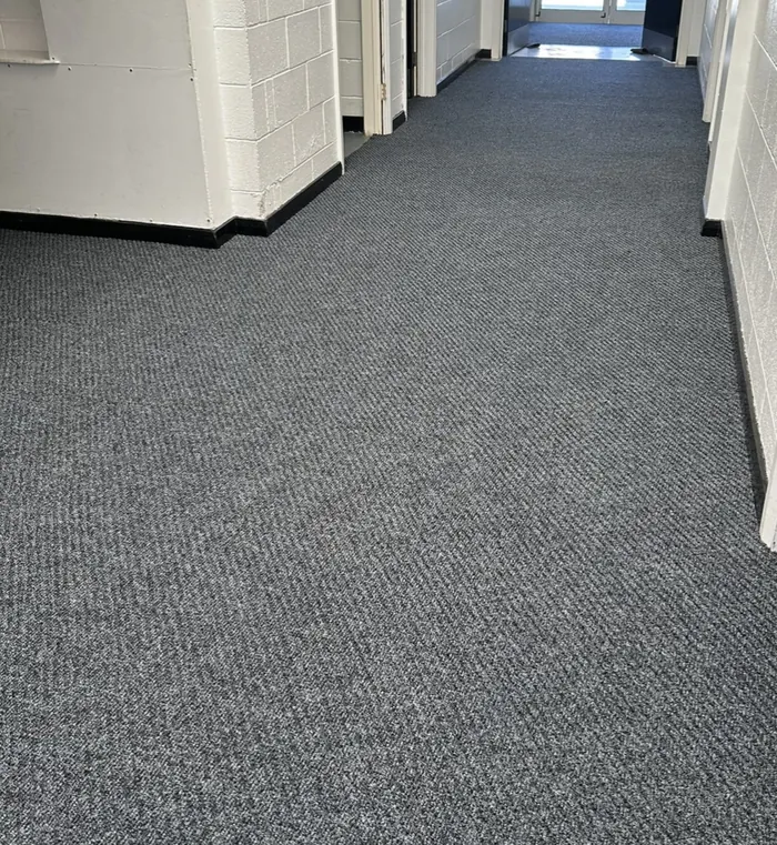 Grey carpet tiles fitted along a school corridor in Bridlington beside white walls and classroom doorways