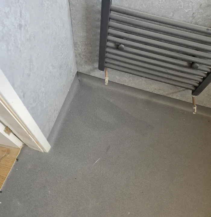 Another view of the same grey Altro Aquarius wet-room floor, with coved edges beneath a towel radiator